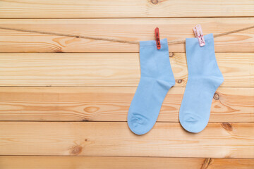 multicolored socks hanging on a clothesline with clothespins on a light wooden background