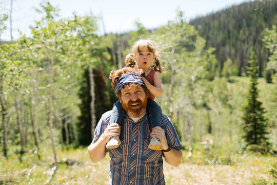 USA, Utah, Uinta National Park, Portrait of smiling man carrying daughter (2-3) on shoulders in landscape