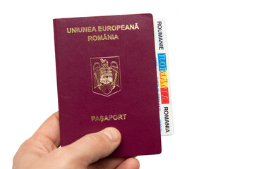 Romanian passport in hand, isolated on white background.