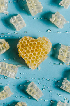 From above of bright heart shaped honeycomb with delicious honey on blue background