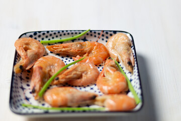 Boiled shrimps on square white and blue plate with green scallion