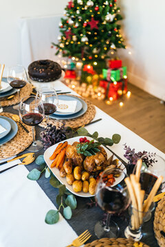 From above of yummy chicken with baked vegetables near glasses of red wine during festive event