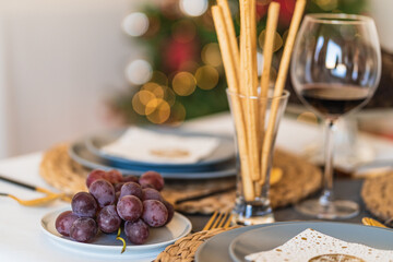 Tasty grapes near glass with crunchy bread sticks and red wine on Christmas day