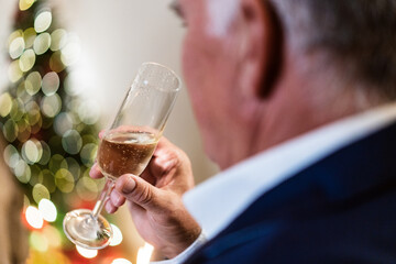 Cropped unrecognizable male in festive outfit sitting with glass of champagne during Christmas celebration