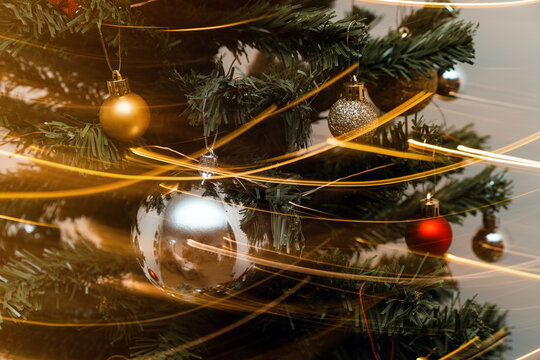 Detail of Christmas tree with decorative colorful balls and glowing garland in long exposure