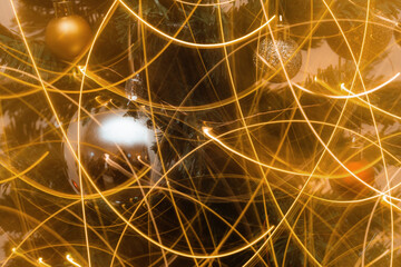 Detail of Christmas tree with decorative colorful balls and glowing garland in long exposure