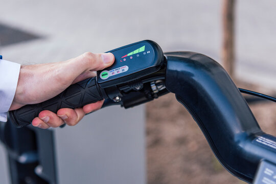 From above of crop anonymous male touching LCD display with colorful symbols on electric bicycle