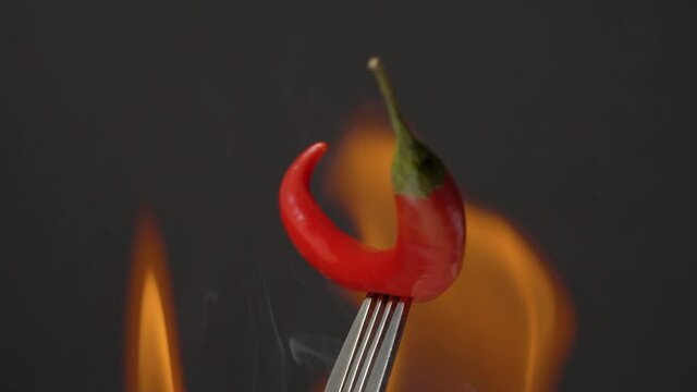 Close up hot chili pepper in fire rotating on black background
