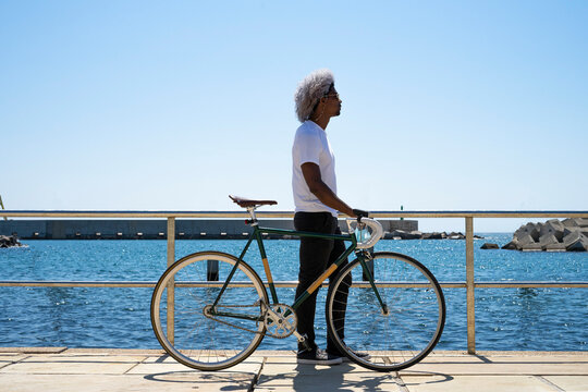 Black man with afro hair carrying a city bike. Biker riding with his bike next to him.