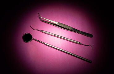 From above of various dental instruments arranged in row on pink table in clinic