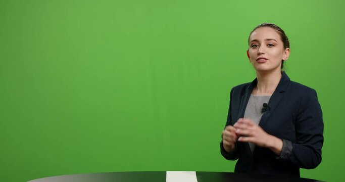 Professional female journalist talking into a camera and expressively gesturing. Beautiful woman presenting a product in commercial. Shot on green background 4k footage