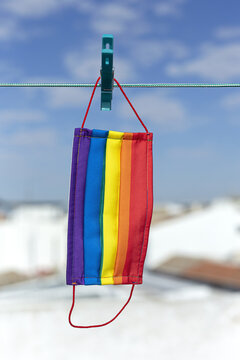 Protective mask with picture of LGBT rainbow flag attached with clothespin to thread on sunny day in backyard