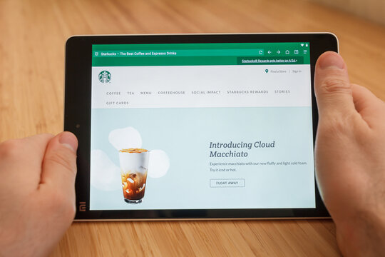 SAN FRANCISCO, US - 1 April 2019: Close up to hands holding tablet using internet and looking through Starbucks web site, in San Francisco, California, USA. An illustrative editorial image.
