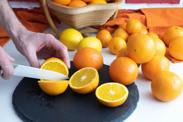 there are a lot of oranges on the table, a man cuts an orange in half