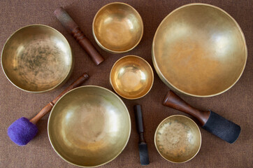 Top view of tibetan singing bowls with sticks on the dark background - music instruments for meditation, relaxation, yoga, massage, sound healing
