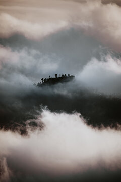 Dramatic scenery of dark mountain top seen through dense gray clouds and fog in highlands