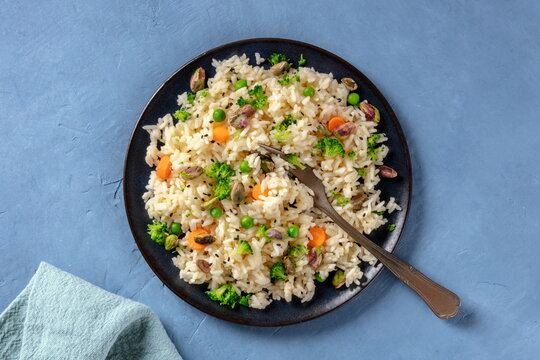 Vegan rice with vegetables, healthy and delicious, the plate is shot from above on a blue background