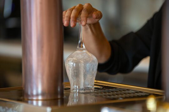 Crop anonymous barman using rinser for cleaning wineglass while working in modern bar