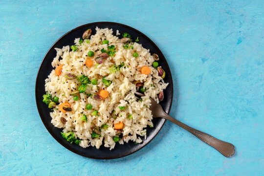 Vegan rice with vegetables, healthy and delicious, shot from the top with copy space on a blue background