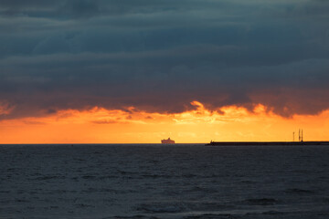 Naklejka na ściany i meble Dramatic sunset sky over the sea and the pier.