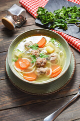 Meatball soup and ingredients on wooden table.