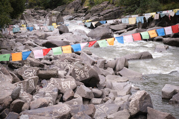Sanskrit mantra Om Mani Padme Hum engraved on surface of big grey stones in mountain river in village of Baiyu in China