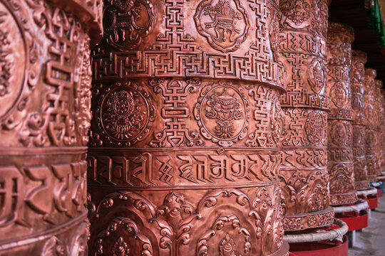 Tourists in traditional authentic Buddhist temple for worship with mantras on prayer wheels in Tibetan Buddhist temple