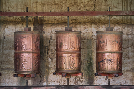 Old stone Tibetan rolls with sacred mantra consisting of sanskrit inscription near temple