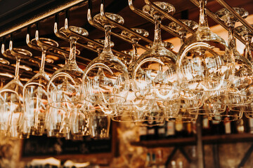 Low angle of shiny crystal glasses hanging on metal rack over bar counter