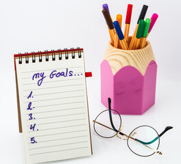 My goal concepts with text on notepad with accessories on white desk table background