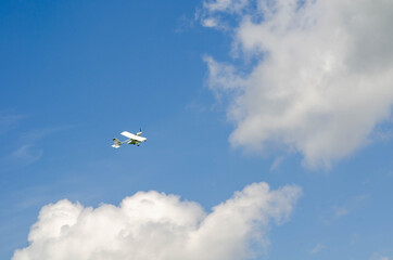 The plane of small aircraft soars, flies in the sky among the clouds.