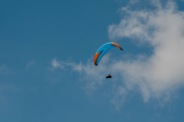 Paraglider flying far in the sky