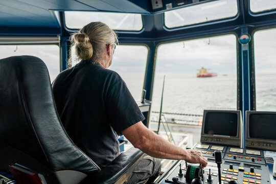Captain of deck Officer on bridge of vessel or ship during navigaton watch at sea . He is maneuvering with cpp thrusters propulsion and bowthruster