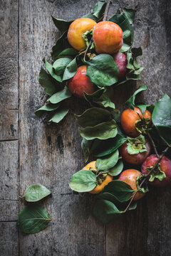 Top view composition of twigs with sweet ripe persimmon fruits placed on gray wooden table
