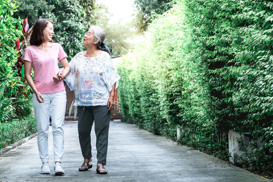 Portrait images of An elderly mother and daughter take a walk in the park happily, to relationship of family and health care concept.