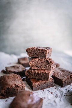 Pile of tasty soft brownie pieces on parchment near shiny wall in house