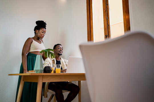 Black self employed man and woman using laptop while doing job remotely from home