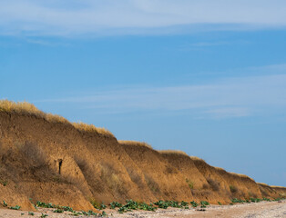 Beautiful clay mountains of the sea coast against a blue sky with Cirrus clouds. You can use as the background of the postcard.