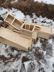 Open wooden mailboxes are heaped outside in the snow.