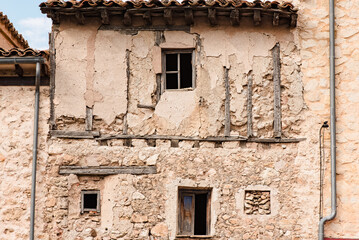 Exterior of aged abandoned building with crumbling stone walls and small windows located on street of medieval town Cuenca in Spain