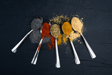 Fototapeta na wymiar Spices in metal spoon on black background