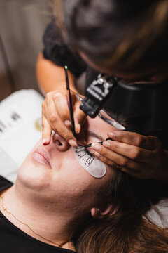 From above of crop anonymous master doing eyelash extension after mapping for unrecognizable female customer in face mask