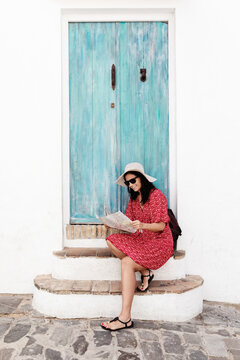 Content female traveler in sunglasses with map near old building in Rhodes in Greece