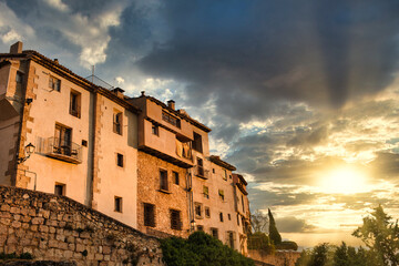 From below facade of old weathered stone residential building located on street of Cuenca town in Spain against cloudy sky at sunset time