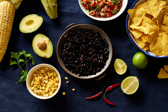Ingredients for cooking chilaquiles - black beans, tortilla chips, corn and salsa