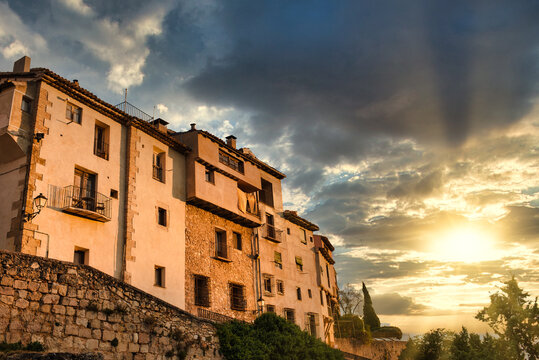 From below facade of old weathered stone residential building located on street of Cuenca town in Spain against cloudy sky at sunset time