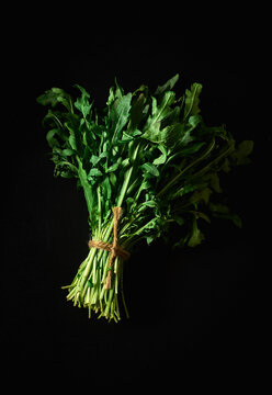A bunch of fresh rocket salad on black background