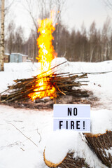 The concept of nature protection, protection from forest fires, ecology. Open fire warning.A sign with the text No fire against the background of a large blazing fire.