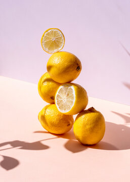 Creative composition of fresh lemons stacked in shape of pyramid on pink background in studio