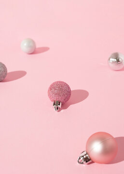 From above of decorative Christmas baubles arranged on pink background in studio for holiday celebration